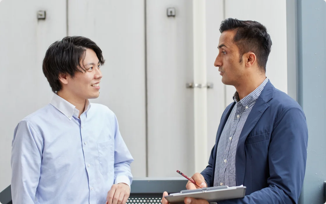 資料を手に打ち合わせをする2人のスタッフ