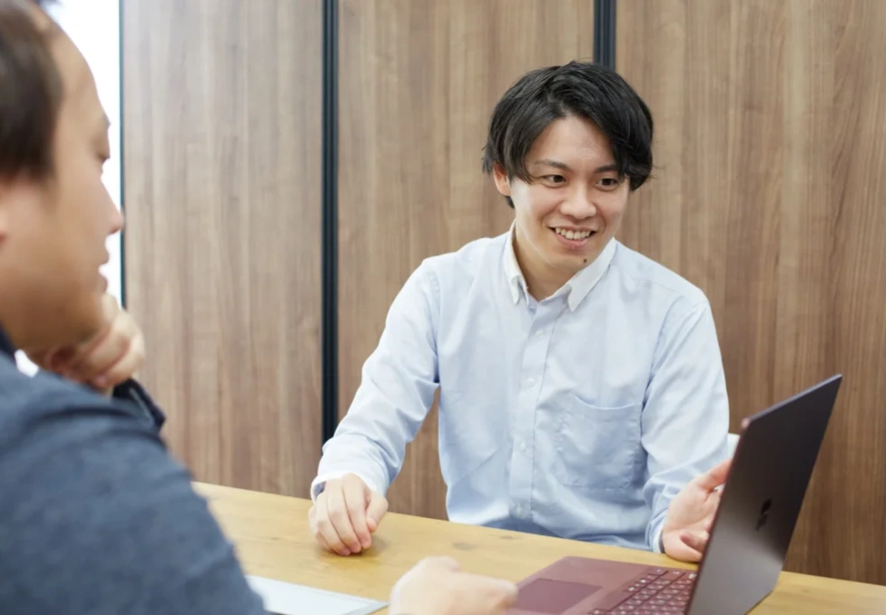 ノートパソコンを囲んで話し合うスタッフ